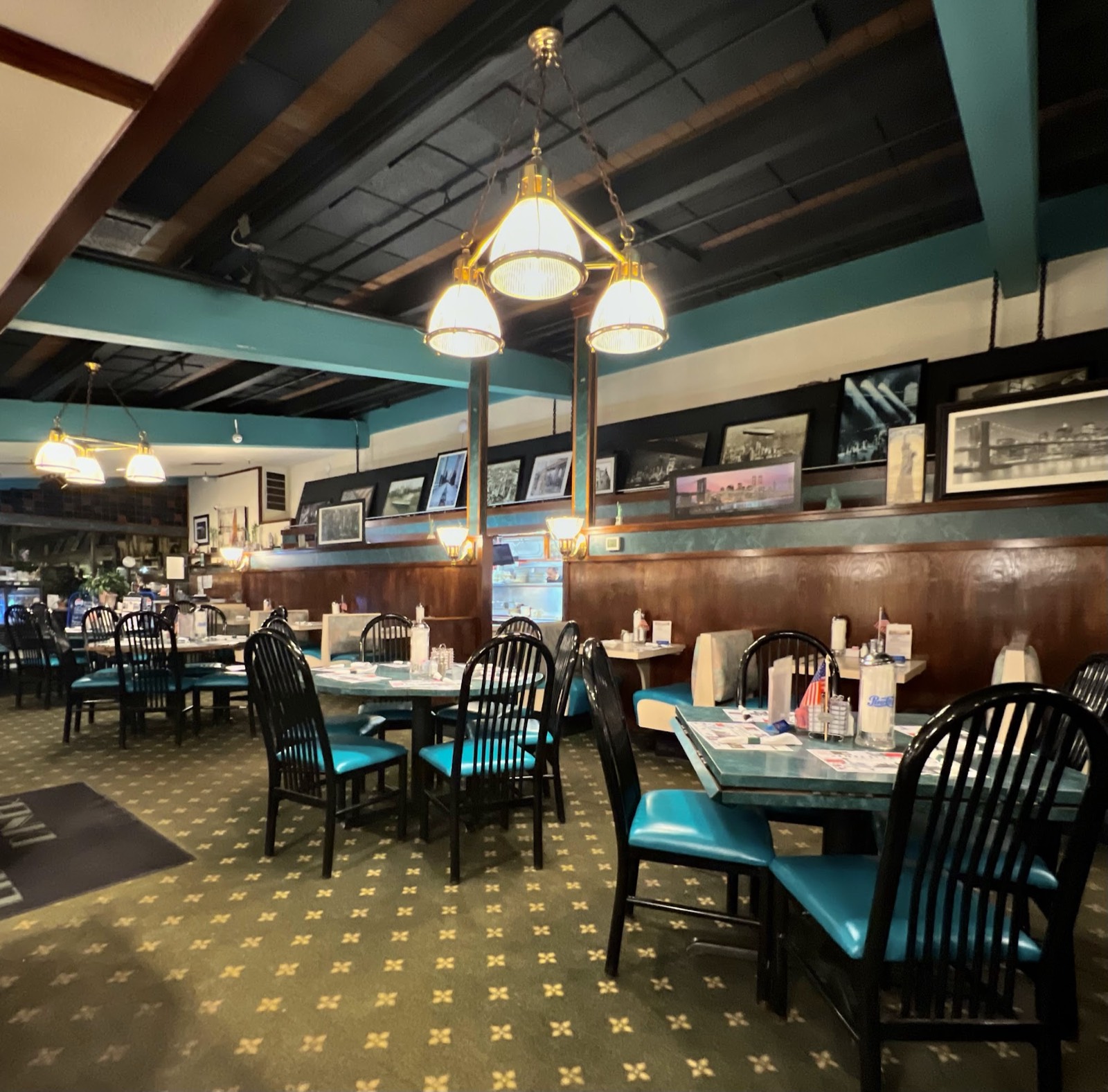 Dining room with teal chairs, dark wood beams and framed New York photos